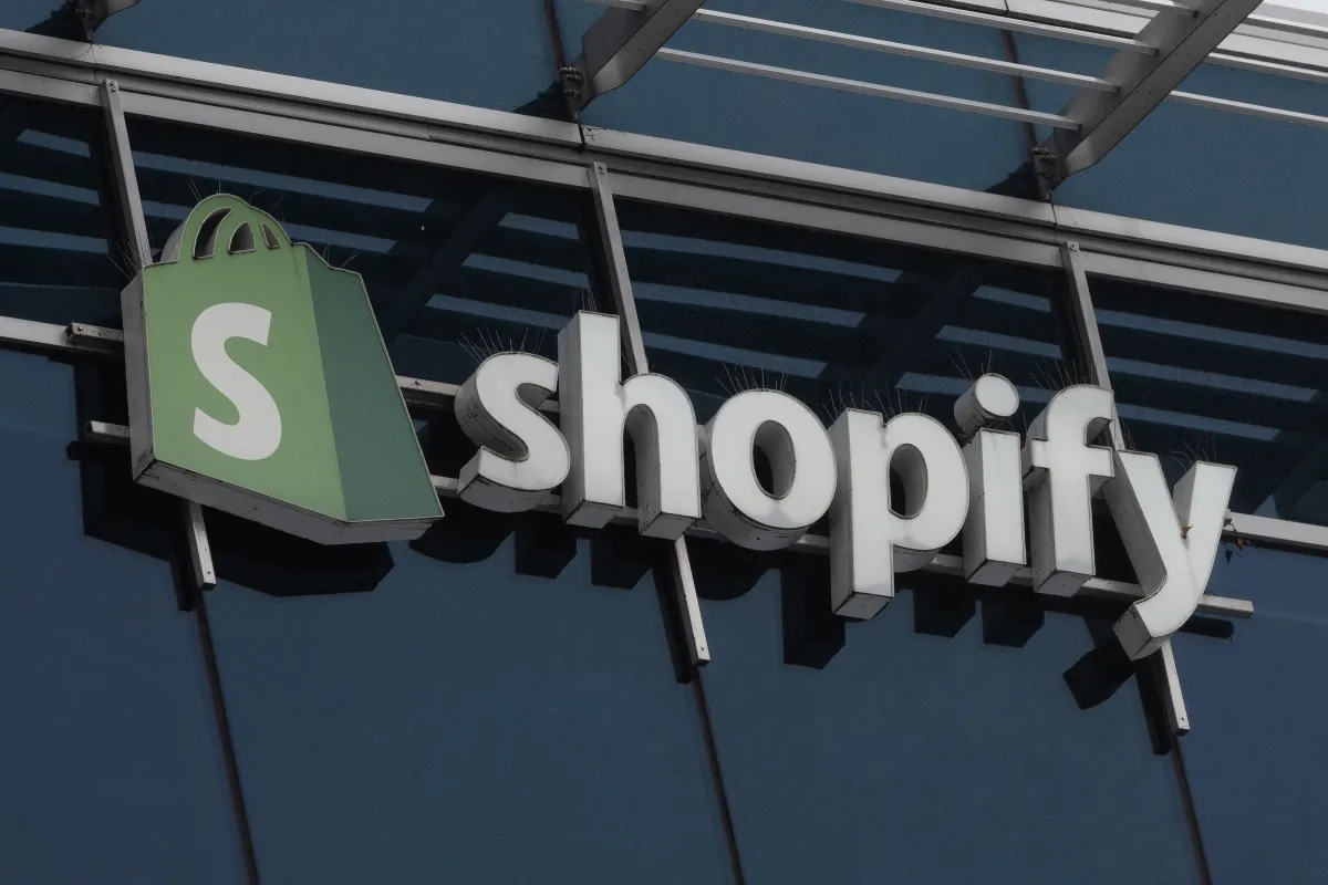Логотип Shopify на экране с интерфейсом оформления заказа и AI-агентом